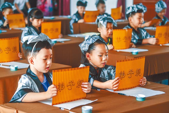 108课纲上路衍伸诸多问题，甚至连小学的古典诗文内容比例也大幅下降。对比大陆，浙江省湖州市东林镇泉心村文化礼堂举办「传承经典 明礼感恩」开蒙礼活动，吸引当地小朋友参与，诵读弟子规。    （新华社）