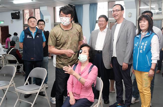 创立「银光未来创新协会」的朱立伦（右二）和县长杨文科（右三），看验光师为长辈检查视力。（罗浚滨摄）