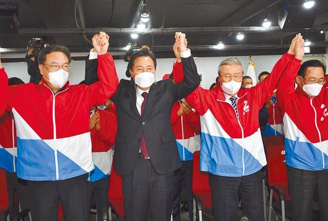 韩国7日举行首尔市和釜山市市长补选，国民力量党首尔市长候选人吴世勋（左二）与党友们观看开票结果时高举双手，显示胜券在握。（美联社）