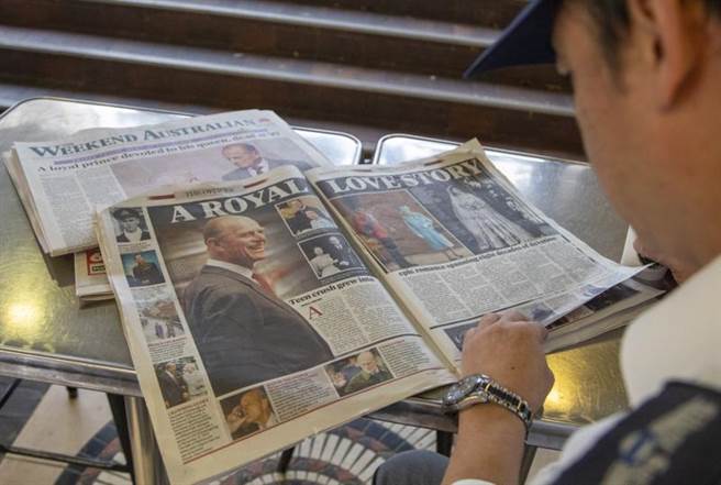 菲立普离世碰上新冠大流行，如何拟定丧礼出席名单让王室伤透脑筋。图为英国民眾浏览媒体报导女王爱情故事。(图/美联社)