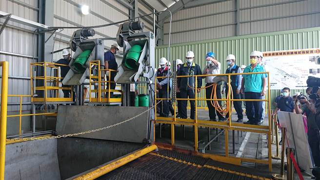 台南市长黄伟哲（深蓝夹克黄领者）在高速发酵机旁听取运转程序简报。（程炳璋摄）