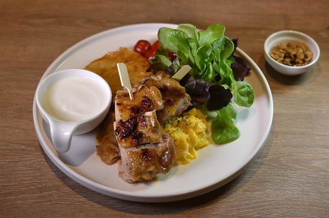 〈M One Cafe〉的〈橙香雞腿排早餐〉，雞腿排是用柳橙汁醃漬入味後再炙烤，套餐並附炒蛋、薯餅、燕麥優格與沙。（圖／姚舜）