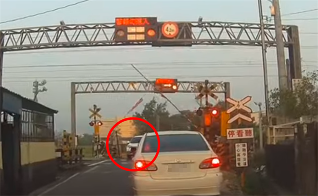 驾驶见遮断杆已升起就往前开，没想到遮断杆又再次放下，导致轿车当场卡在平交道。（图／翻摄自爆料公社影片）