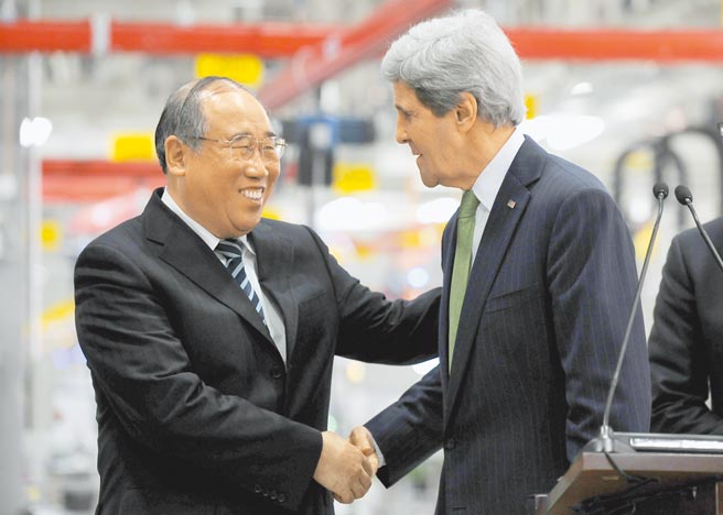 美國氣候特使凱瑞（右）14日抵達上海，將與中國氣候變化事務特使解振華（左），討論美中氣候合作的新機制；圖為2014年凱瑞訪中時與解振華握手致意。（中新社）