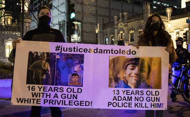 示威者举牌抗议，芝加哥警方射杀举起双手的13岁墨西哥裔少年，但持枪的16岁白人少年却没事。（美联社）
