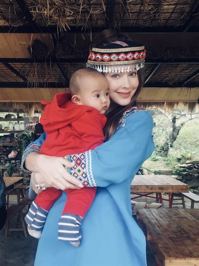安妮穿上原住民传统服饰，手上抱着小孩。（伊林提供）