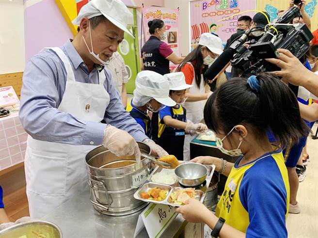 渔业署22日在嘉义县菁埔国小举办「百年好蛤国产优鱻」启动记者会，嘉义县长翁章梁帮学童打菜，共享营养午餐。（吕妍庭摄）