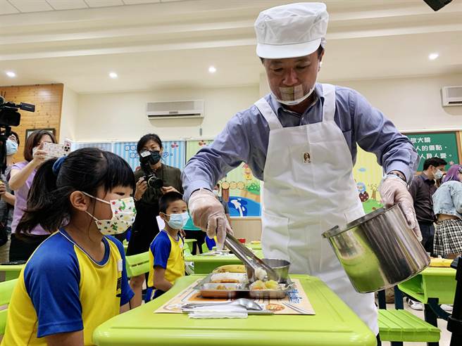 渔业署22日在嘉义县菁埔国小举办「百年好蛤国产优鱻」启动记者会，嘉义县长翁章梁帮学童打菜，共享营养午餐。（吕妍庭摄）