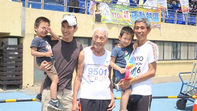张文吉完成100公尺短跑赛事后，在终点处和儿子、孙子、曾孙合照，因心情愉快，又有四代同堂应援团，成绩比平时练跑更好。（谢琼云摄）