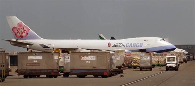 在桃园机场的货机坪上，1架华航747-400货机旁堆满准备装载的货物。（范扬光摄）