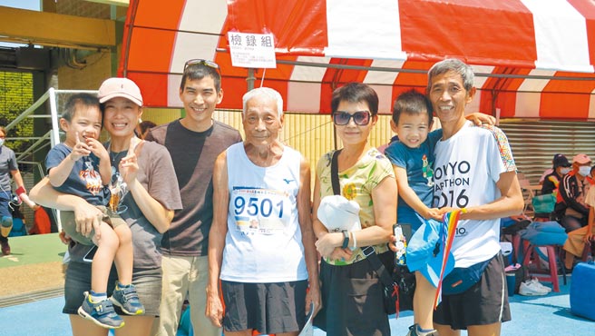 96岁彰化市民张文吉（中）在儿子张仁录（右）鼓励下，报名参加全国常青田径赛，成为今年全场所有比赛项目中最高龄参赛选手；一家四代全到场边为他加油。（谢琼云摄）