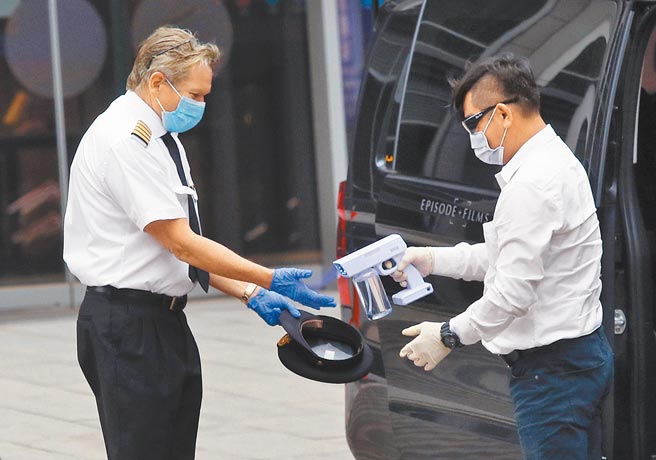 桃园医院防疫团队昨日起在华航园区设临时医疗站，执行採检、抽血及疫苗接种等作业，1名机师离开机场防疫旅馆，上车前消毒双手及随身物品。（范扬光摄）