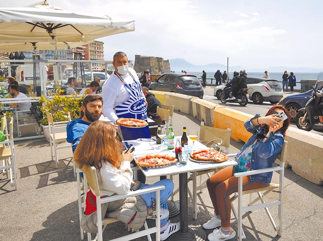 26日起，義大利多地進入疫情風險相對較低的「黃區」，疫情管控措施放寬。圖為遊客在那不勒斯一家餐廳的戶外用餐區用餐。 （新華社）