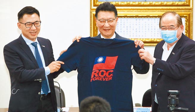 国民党28日中常会邀请中广董事长赵少康（中）专题演讲「和平、奋斗、救台湾」，主席江启臣（左）在演讲后赠送绣有国旗的T恤，写着永远的中华民国英文字样，表达感激。图右为国民党秘书长李乾龙。（郑任南摄）