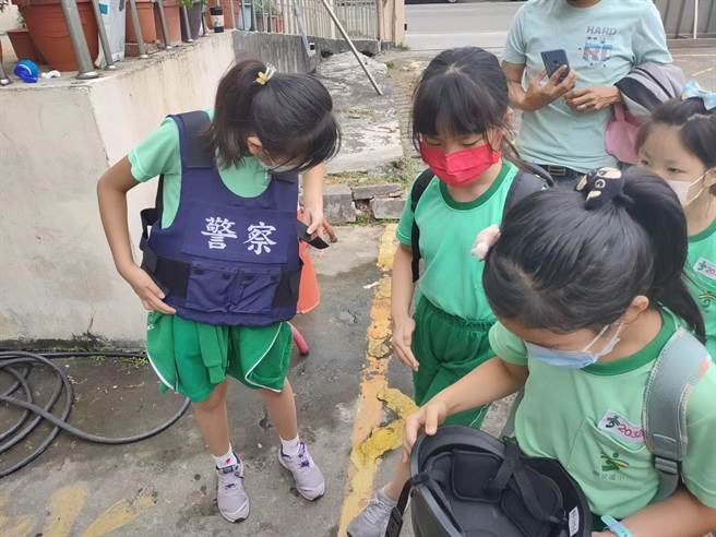 小朋友亲身穿戴警用防弹背心、头盔及试拿盾牌等感到新奇。（卢金足摄）
