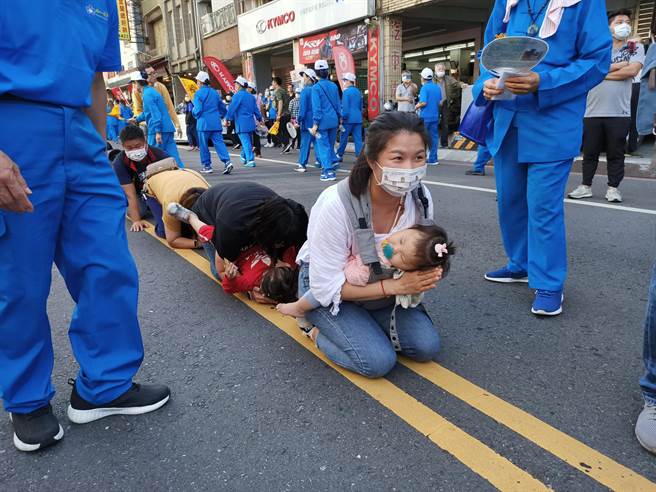   这名年轻的妈妈抱着熟睡的孩子一起「钻轿底」。（胡健森摄）