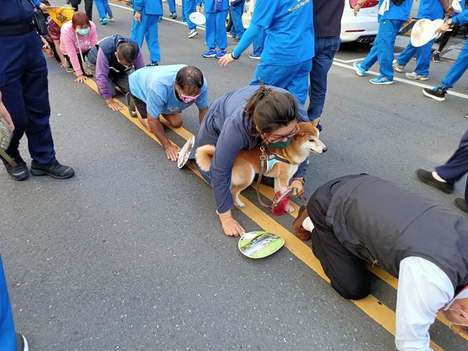  这名女子带着爱犬一起「钻轿底」。（胡健森摄）