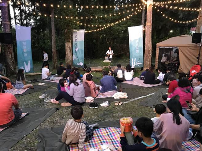 「2021南投萤火虫季」活动闪亮登场，1日晚间举办溪头萤光派对，歌手在山林间演出，游客席地而坐，赏萤听歌。（南投县政府提供／卢金足南投传真）