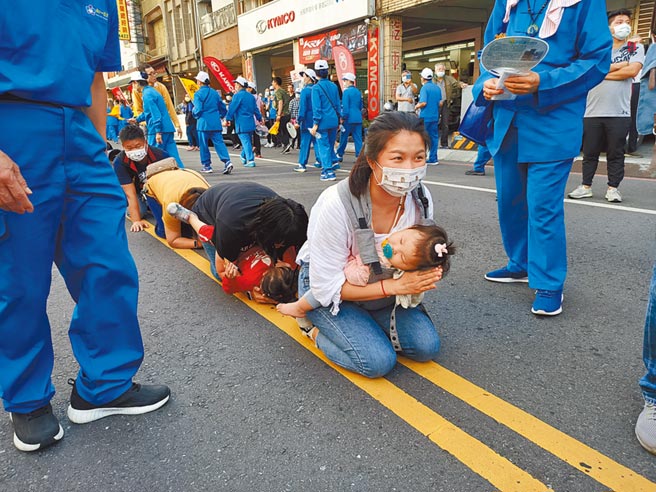 这名年轻的妈妈抱着熟睡的孩子一起「钻轿脚」。（胡健森摄）