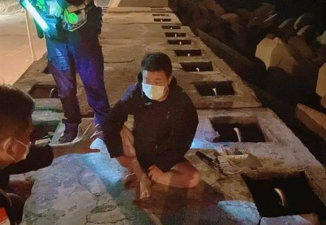 大陆籍周姓偷渡客蹲坐在台中港西码头防波堤，他自称在大陆没有犯罪，来台是为「投奔自由台湾」。（读者林学贤提供／王文吉台中传真）