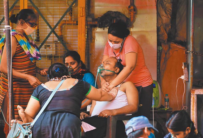 印度疫情持续恶化导致医疗物资缺乏，尤其急缺氧气。图为一名新冠肺炎患者呼吸困难，他的家人帮忙按摩他的胸口。（路透）