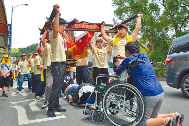 三峡兴隆宫睽违2年举行妈祖遶境，轿班将妈祖轿子抬起，让身障民眾能钻轿底，祈求神明庇佑。（蔡雯如摄）