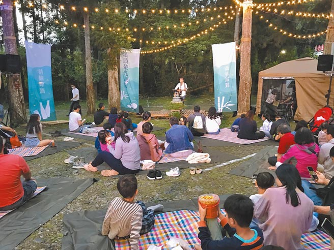 「2021南投萤火虫季」活动闪亮登场，1日晚间举办溪头萤光派对，歌手在山林间演出，游客席地而坐，赏萤听歌。（南投县政府提供／卢金足南投传真）