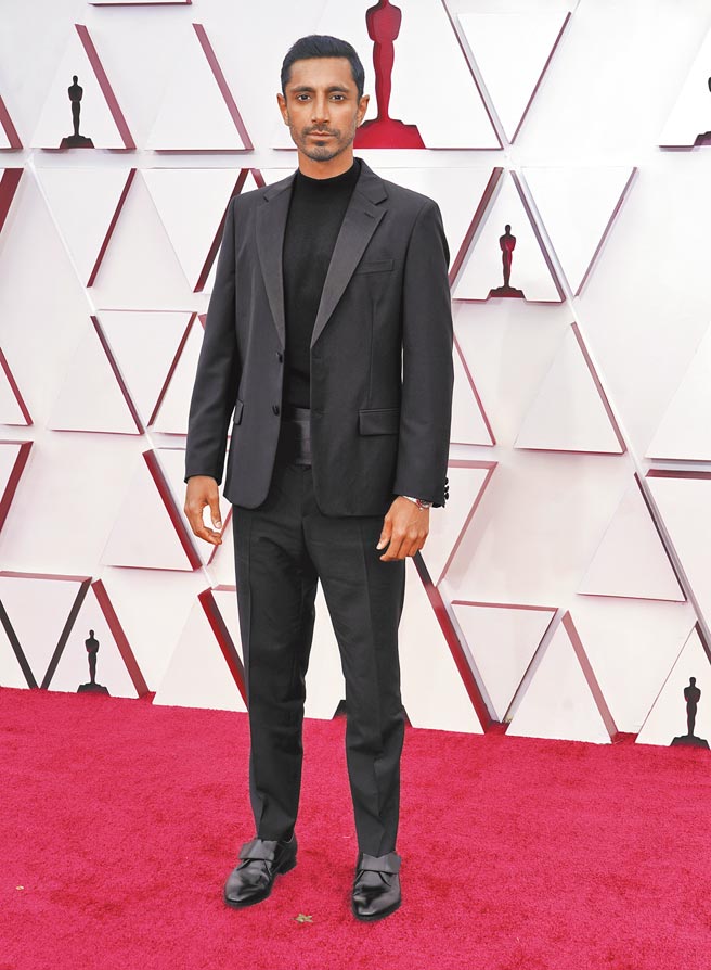 里兹阿迈德穿PRADA黑色燕尾服搭黑色羊毛高领毛衣，展现时尚好品味。（美联社）