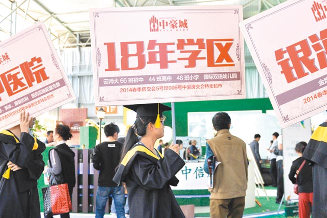 大陆中共中央政治局上月底召开会议罕见提及「学区房」，强调坚持房子是用来住的、不是用来炒的定位，点名防止以学区房等名义炒作房价。图为大陆房屋销售员举着学区房宣传牌。（中新社）