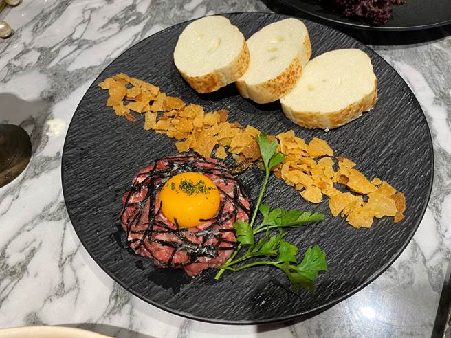 生牛肉塔塔：选用日本和牛与澳洲和牛各半，细工手切，拌入特制烧肉酱，撒上虾夷葱提味，将饱满浓郁的灵芝蛋黄与生牛肉、油条碎拌匀享用，口感酥脆交错，亦可搭配炭烤至外酥内软的起司软法享用。（冯惠宜摄）