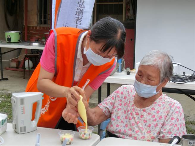 脑麻孩子照顾者陈妈妈（左）昨天到嘉县东石乡港墘弘道失智据点陪同长辈做蛋糕，提前庆祝母亲节。（张亦惠摄）