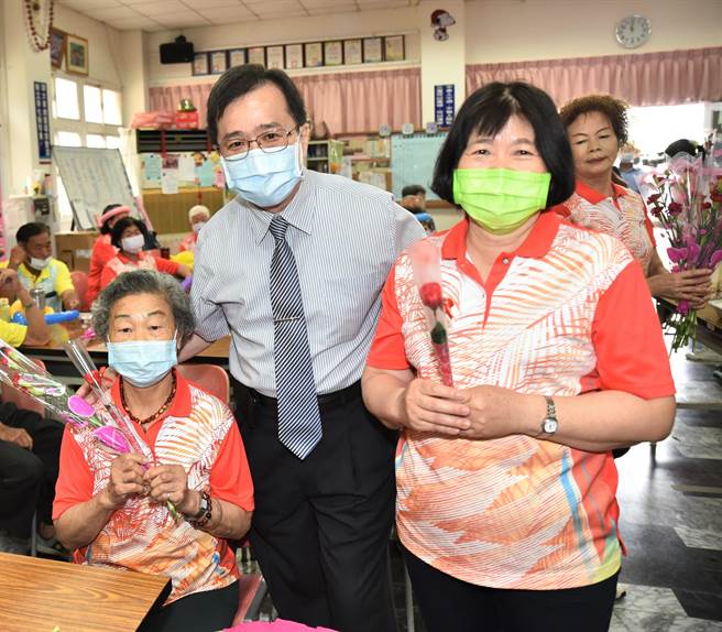 冈山秀传医院院长赵昭钦（左二）4日到永安区出席「健康友善社区」揭牌，他送给长者康乃馨，预祝母亲节快乐。（林瑞益摄）