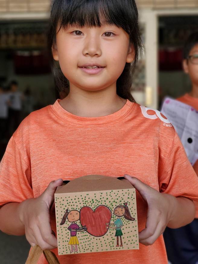 小朋友费心彩绘装饰纸盒和提袋。（周丽兰摄）