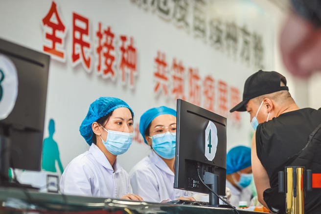 大陆医护人员为接种疫苗的市民登记信息。（新华社）