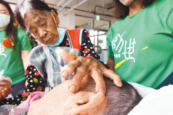 88岁兰屿妈妈5日到创世探望久违的植物人儿子，满布风霜皱纹的手，不时抚触着沉睡6年的爱儿。（庄哲权摄）