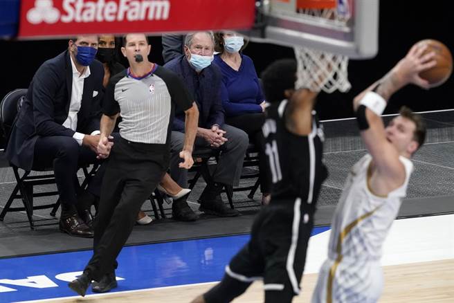 前独行侠球星诺维兹基与前美国总统布希伉俪坐在场边观看比赛。(美联社)