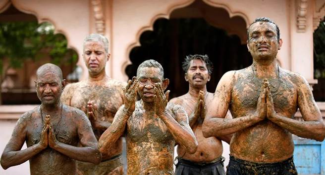 印度人迷信牛粪尿可治新冠，涂满全身，再虔诚祈祷。(图/路透)