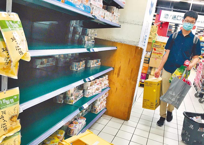 國內爆發社區感染引發恐慌，許多民眾12日紛紛前往賣場搶購民生物資，不少貨架上的泡麵及罐頭都被掃空。（范揚光攝）