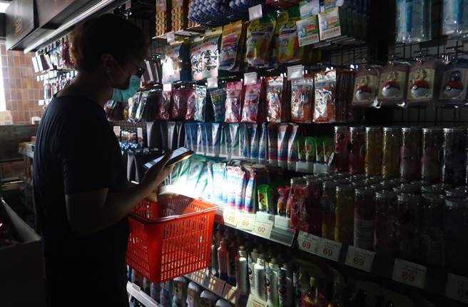 興達電廠13日因事故全廠停機，台北市有許多商家亦停電，民眾摸黑以手機照明選購商品。(資料照/王英豪攝)