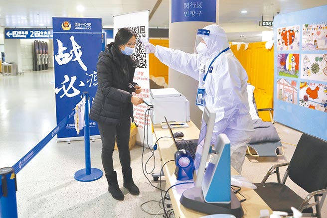 由於大陸安徽和遼寧新冠肺炎疫情再起，上海宣布自今日起實施14天隔離加7天社區健康監測的入境隔離政策，且核酸檢測將增為6次。圖為2月初，上海浦東機場的工作人員為旅客測量體溫。（中新社）
