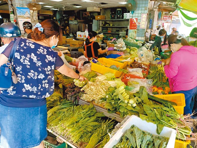 新冠肺炎疫情嚴峻，百業苦哈哈，不過傳統市場的生意反而因此旺到不行。戴著口罩的顧客擠滿了菜攤，挑選新鮮蔬菜。（張毓翎攝）