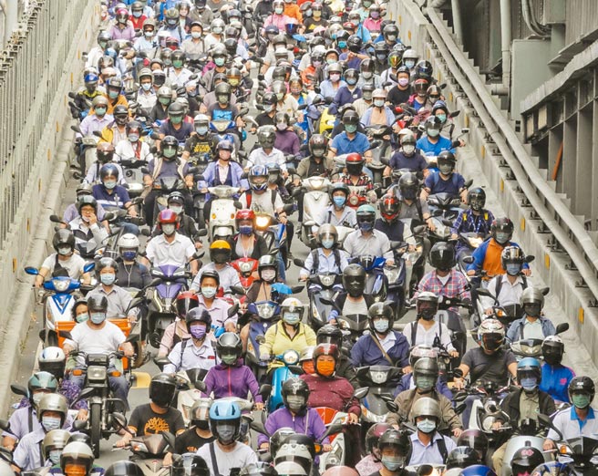 台湾本土疫情持续爆发，短短8天确诊就累计达1024例，最多确诊数仍落在双北，许多民眾都提高警觉加强防疫，连通新北三重与台北大同两区的台北大桥，阵容庞大的通勤机车族几乎人人戴着口罩，但流量惊人的车阵让维持社交距离成为不可能的任务。（黄子明摄）