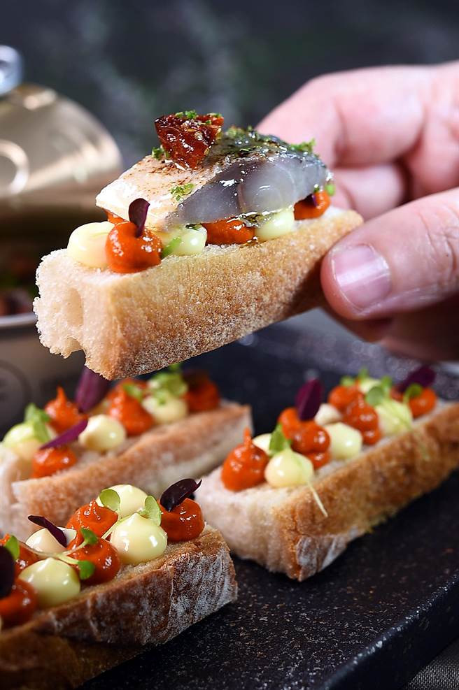 品尝〈醋渍油封竹筴鱼〉可搭配用蛋黄酱与红椒酱提味的麵包，感受被橄榄油包覆的竹筴鱼，滑溜的肉质口感及鲜味。（图／姚舜）