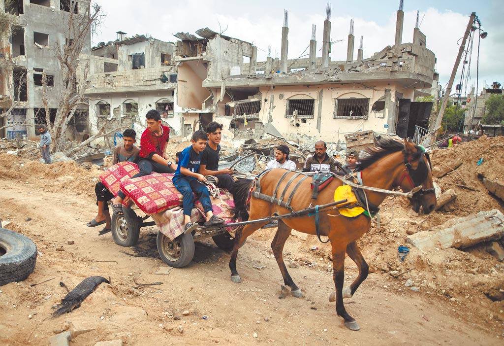 幾名巴勒斯坦人在以色列和巴勒斯坦「哈瑪斯」宣布停火後，搭乘簡陋的馬車，帶著家當返回加薩地區被以色列轟炸過的家園。（美聯社）