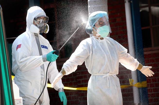 新冠肺炎本土疫情持续蔓延，许多民眾21日前往设在万华青草广场的筛检站採检，站内陆军化学兵正在为护理人员进行全身消毒。（图／范扬光摄）