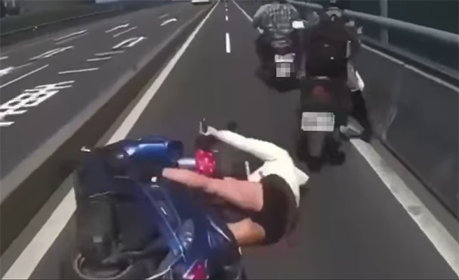 一名女骑士被右侧机车挤到，不慎重心不稳摔倒在地。（翻摄脸书「台湾新闻记者联盟资讯平台」）