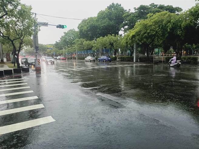 午后雨势变大，机车的民眾都穿起雨衣，民眾出门也撑起雨伞。（张毓翎摄）