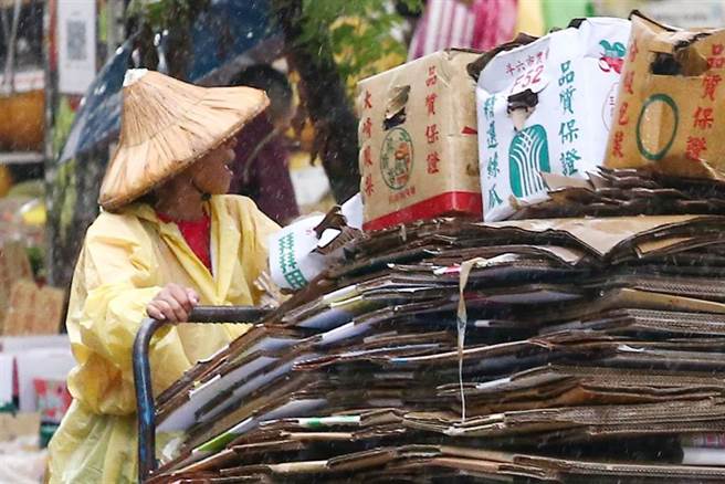 由于锋面笼罩台湾地区，台湾各地31日普遍降下滂沱大雨。图为路上一位妇人在大雨中，整理着被雨打溼的资源回收车。（邓博仁摄）
