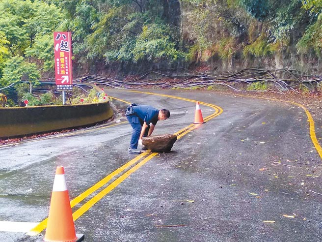 中横公路台8线30日掉落百公斤大石，谷关派出所警员蔡宇杰试图徒手搬移，无奈石头太重，只好通知谷关工务段调派机具清除。（和平分局提供／王文吉台中传真）