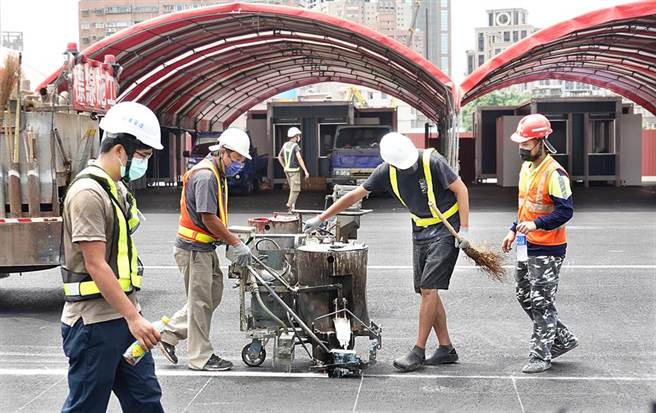 板桥区江翠重画区的大型疫苗接种暨快筛站加速赶工，工作人员在前方停车场忙碌地画设停车位。（姚志平摄）
